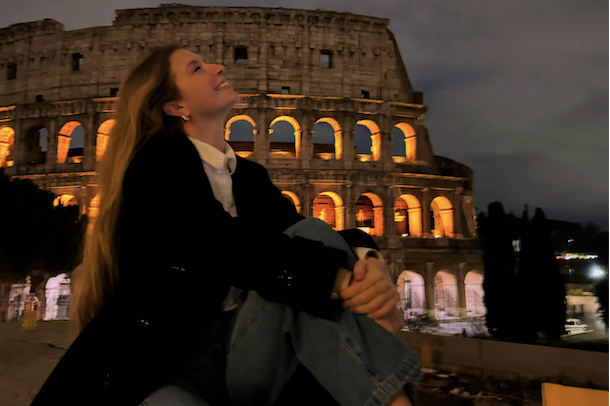 Girl sitting in front of the Colosseum in Rome