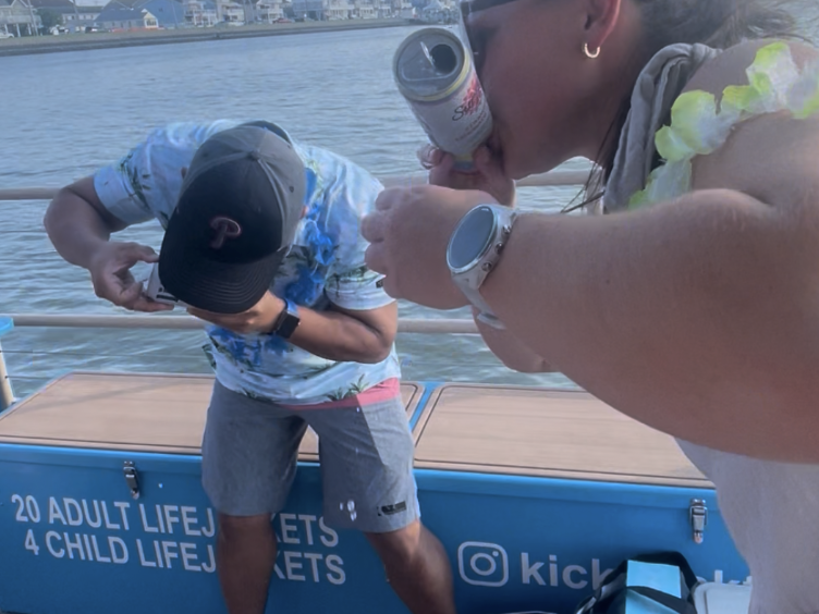 2 people shotgunning beers on a boat