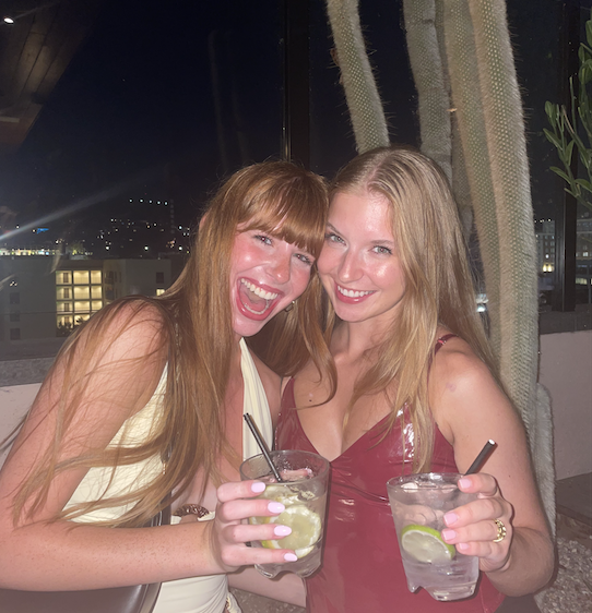 two girls with drinks at a rooftop bar