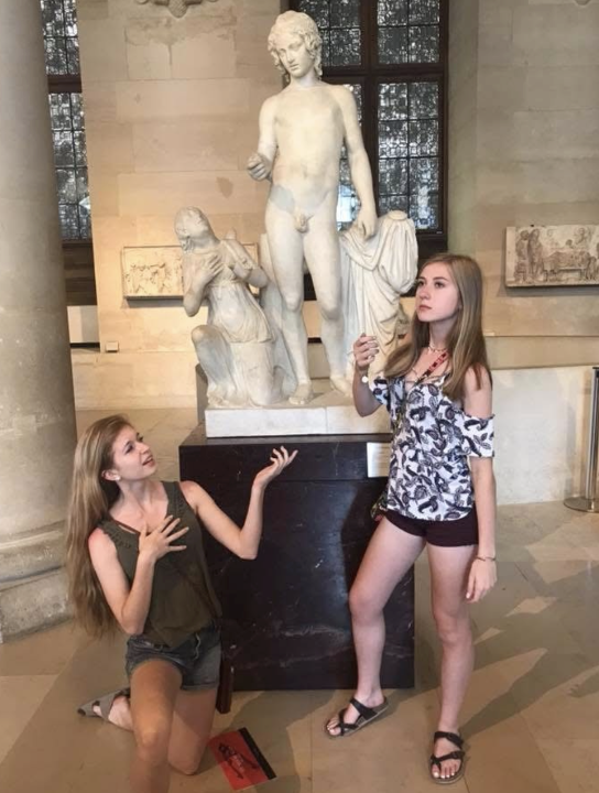 2 girls posing in front of a statue in the Louvre