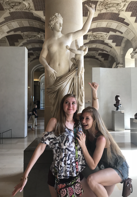 2 girls posing in front of a statue in the Louvre