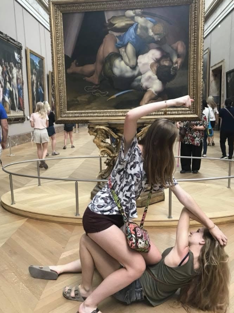 2 girls posing in front of a painting in the Louvre