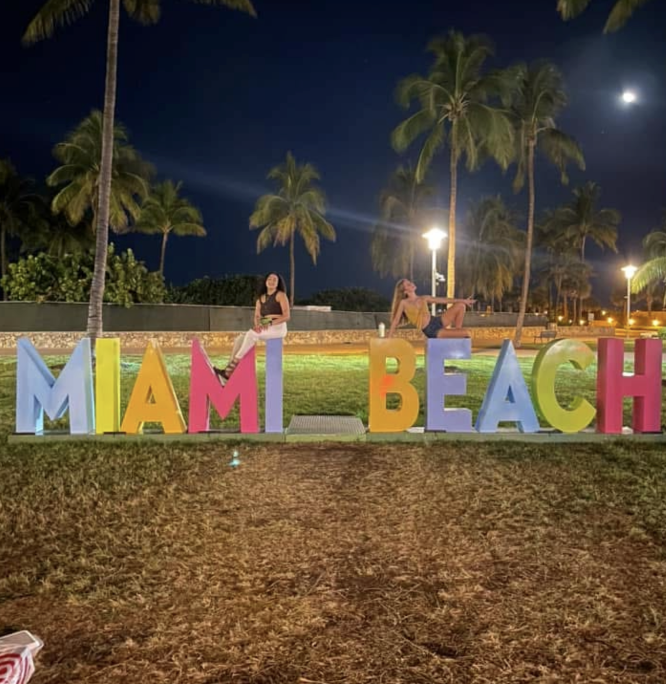 girls posing on miami beach sign on spring break
